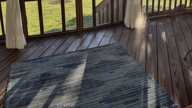 Terraza de madera con vista a un lago y árboles.