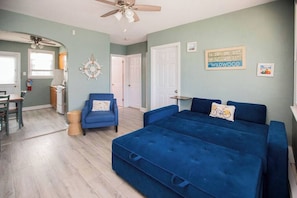 Quarto com cama, cadeira, mesa e ventilador de teto.