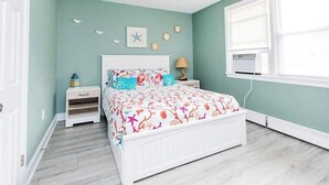 Ein Schlafzimmer mit Türkiswänden, einem weißen Bett und einem Deckenventilator.
