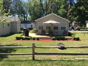 A small, single-story house with a patio, surrounded by a wooden fence. - Gun Lake cabin (Wayland)