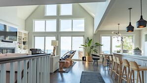 A spacious living area with a large window overlooking the sea, a fireplace, and a dining area with bar stools. - Rare Waterfront Gem In Blue Mountain/Collingwood! Less than 2hrs from Toronto! (The Blue Mountains)