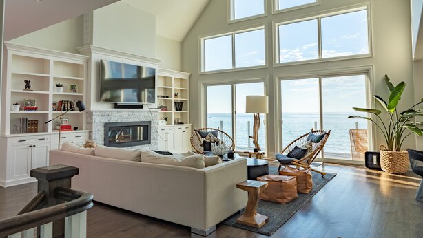 A spacious living room with a fireplace, large windows overlooking the sea, and a modern entertainment setup. - Rare Waterfront Gem In Blue Mountain/Collingwood! Less than 2hrs from Toronto! (The Blue Mountains)