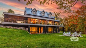 A modern two-story house with large windows, a stone facade, and a well-maintained lawn. - 5 bdrm, 3 bath! Architectural gem! (Huntsville)