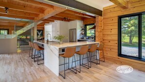 A modern kitchen with a central island, bar stools, and a view of the outdoors. - 5 bdrm, 3 bath! Architectural gem! (Huntsville)