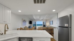 Una cocina moderna con una isla central, un refrigerador de acero inoxidable y vistas al océano.