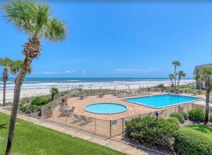 A pool area with a view of the beach, surrounded by palm trees and a fence. - W/D in Unit, Ocean Views Galore, Spectacular Sunrise & Sunset from property (Saint Augustine Beach Florida)