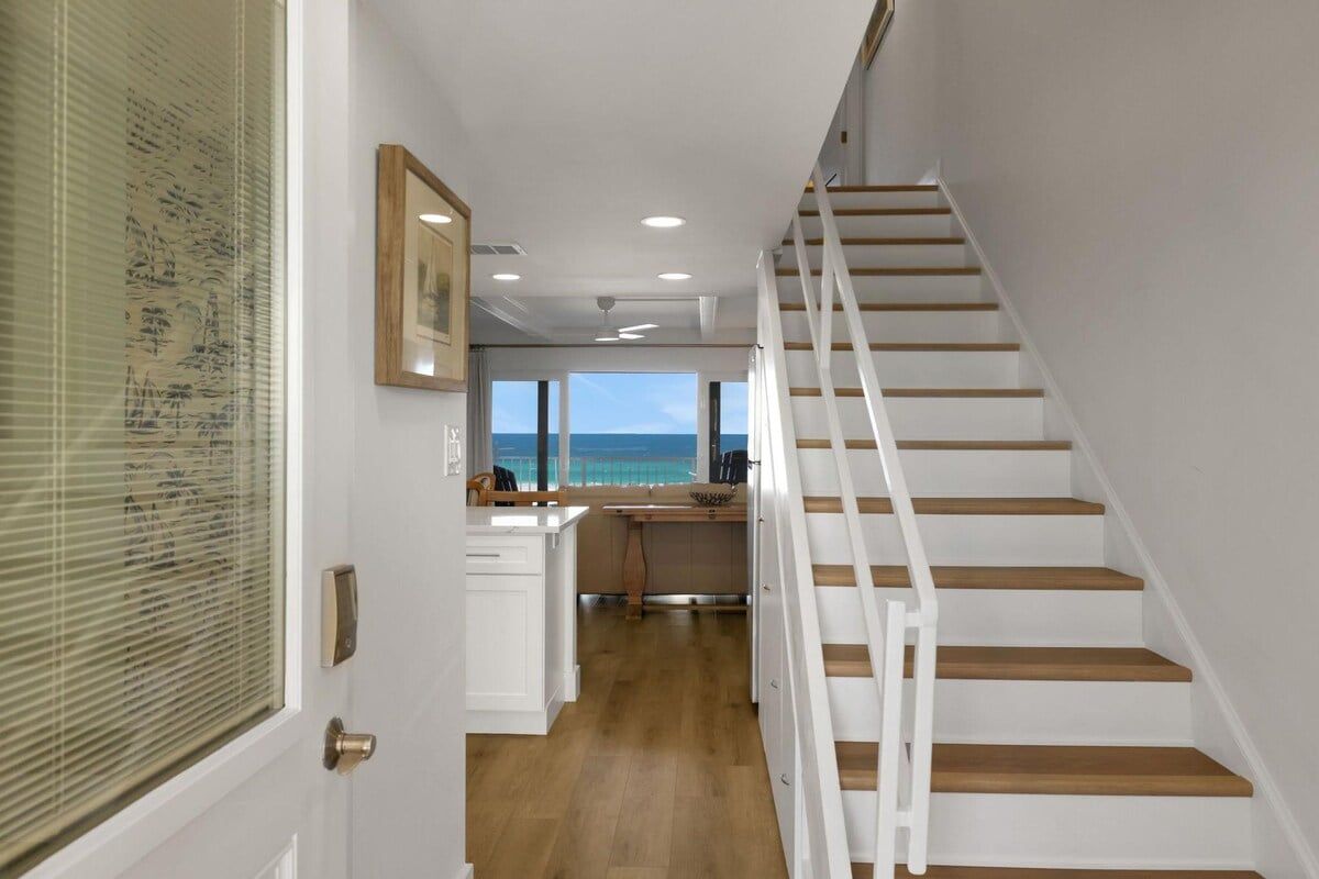 A staircase leading to a kitchen with a view of the ocean.
