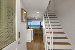 A staircase leading to a kitchen with a view of the ocean. - W/D in Unit, Ocean Views Galore, Spectacular Sunrise & Sunset from property (Saint Augustine Beach Florida)