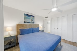 A bedroom with a bed, nightstands, a ceiling fan, and a painting on the wall. - W/D in Unit, Ocean Views Galore, Spectacular Sunrise & Sunset from property (Saint Augustine Beach Florida)