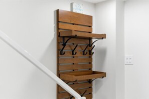 A wooden wall-mounted rack with hooks and a shelf against a white wall, next to a white staircase. - W/D in Unit, Ocean Views Galore, Spectacular Sunrise & Sunset from property (Saint Augustine Beach Florida)