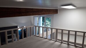 A spacious balcony with a wooden floor and white railing, overlooking a garden. - Lovely studio in the heart of the historic center (Montpellier)