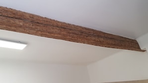 A room with a wooden beam ceiling, white walls, and a fluorescent light fixture. - Lovely studio in the heart of the historic center (Montpellier)