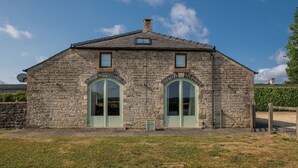A stone building with two arched windows and a small dormer window on the roof. - Oldbury Barn - sleeps 11 guests  in 4 bedrooms (Cheltenham)