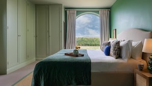 A bedroom with a bed, a bedside table, a window with curtains, and a view of greenery outside. - Oldbury Barn - sleeps 11 guests  in 4 bedrooms (Cheltenham)
