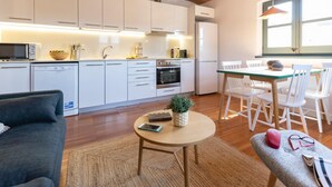 A modern kitchen with white cabinets, a dining area with a table and chairs, and a living room with a sofa and a coffee table. - Bravissimo Raïms Penthouse, with 2 bedrooms (Girona)