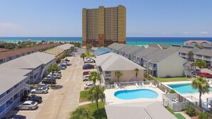 A hotel with a swimming pool, parking lot, and ocean view.