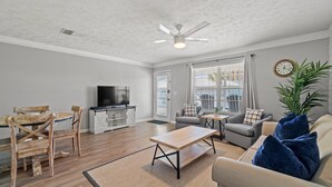 A living room with a wooden coffee table, a sofa, a TV, and a ceiling fan.