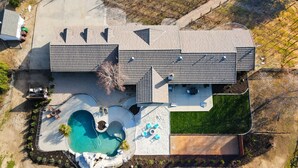 Een modern huis met twee verdiepingen, een zwembad, terras en omheinde tuin.
