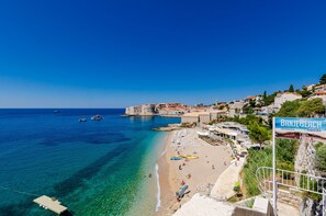 A coastal town with a clear blue sea, a sandy beach, and a historic fort overlooking the water. - Room Mimi - Double Room with patio and sea view (Dubrovnik)