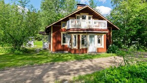 A two-story wooden house with a balcony, surrounded by lush greenery and trees. - Piennarpää by Interhome (Saarijärvi)