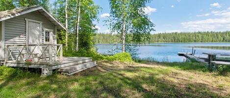 A cabin with a deck and a dock extending into a lake, surrounded by trees.