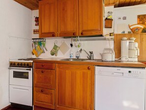 Una cocina con armarios de madera, estufa, fregadero y lavavajillas.