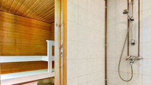 A wooden cabin with a sauna, a bench, and a shower area with tiled walls and a wooden ceiling. - Piennarpää by Interhome (Saarijärvi)