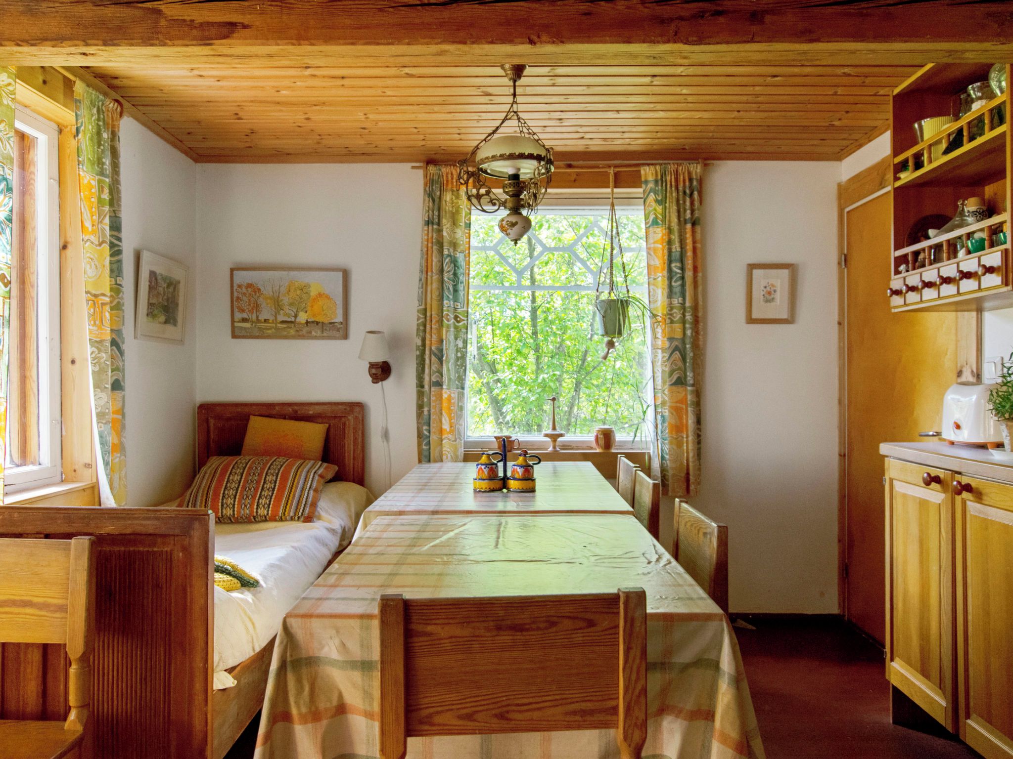 Una habitación acogedora con cama, una mesa y ventana con cortinas.