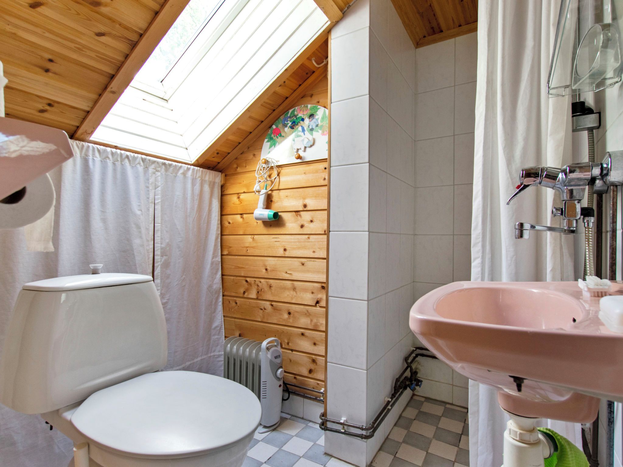 Ein kleines, kompaktes Badezimmer mit Oberlicht, Toilette, Waschbecken und Dusche.