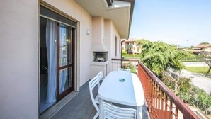 Ein Balkon mit Tisch und Stühlen, eine Schiebetür und Blick auf eine Wohngegend.
