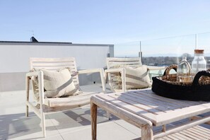A rooftop terrace with two wooden lounge chairs, a small table, and a wicker basket. - The Carlton Apartments (Christchurch)
