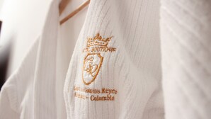 Un vêtement blanc orné de motifs brodés et d’un blason.