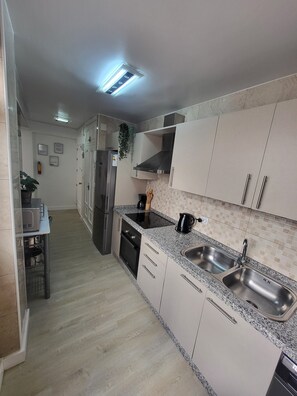 Een koelkast, keukenrol, eettafels