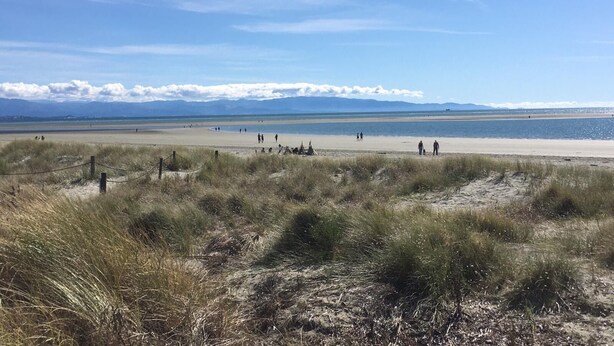 A wide beach with people walking, a clear sky, and distant mountains. - Self contained unit. By the beach and golf course  only 2.2 kms to town centre (Motueka)