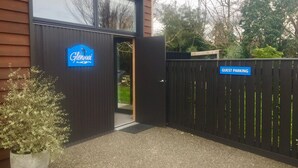 A hotel entrance with a sign reading "Glennway" and a "Guest Parking" sign on a gate. - Self contained unit. By the beach and golf course  only 2.2 kms to town centre (Motueka)