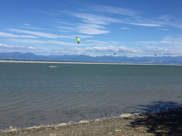 Uma praia com águas calmas e montanhas ao longe.