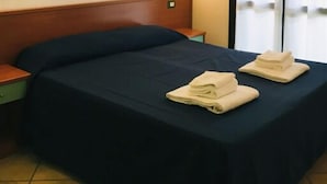 A hotel room with a bed, a nightstand, a painting on the wall, and a window with curtains. - Alba 4 pers. - One Bedroom Resort, Sleeps 4 (Lido di Spina)