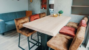 Una sala de estar moderna con una mesa de madera, bancos acolchados, un sofá azul y una estantería.