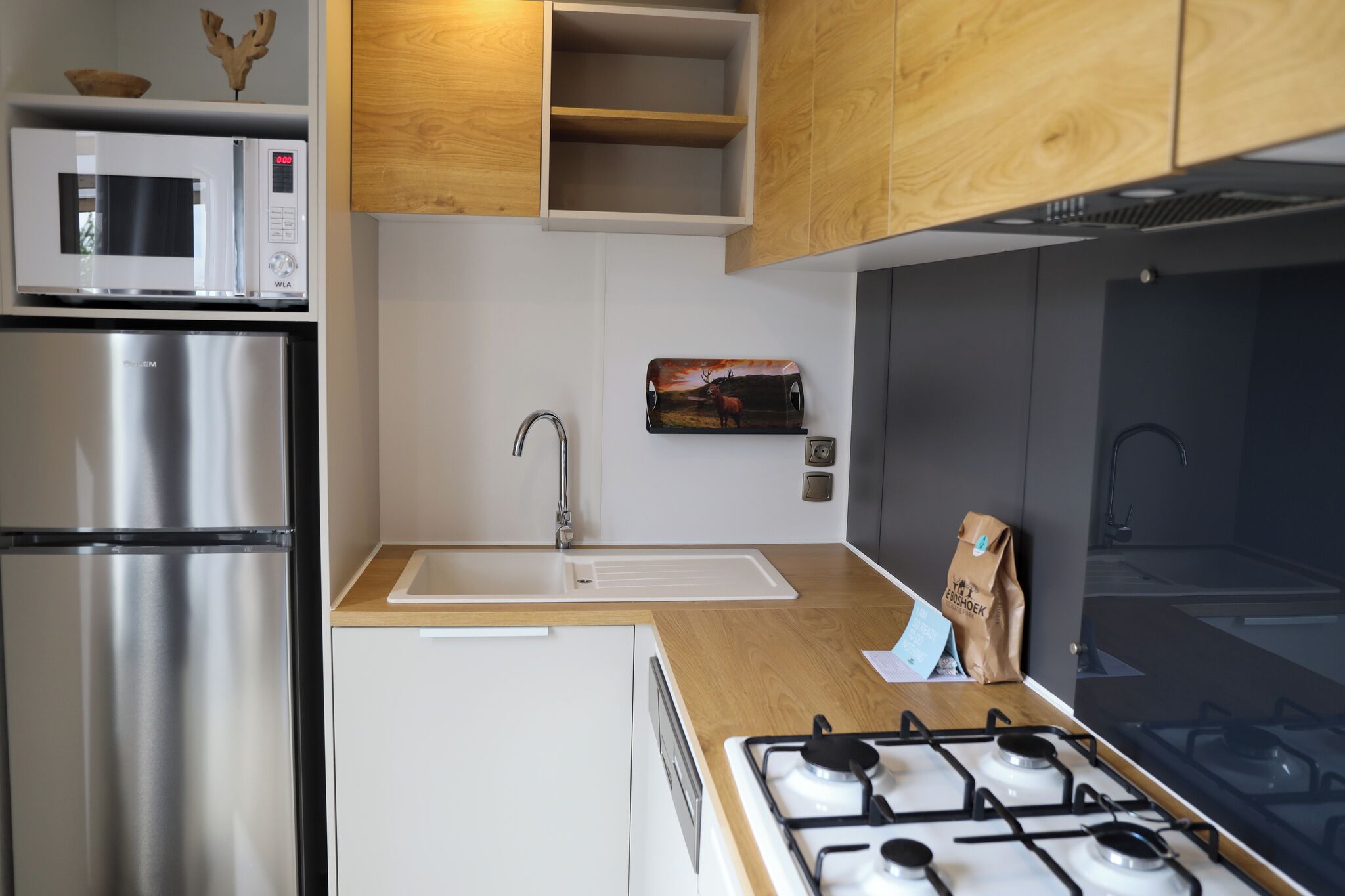 Een moderne keuken met roestvrijstalen apparatuur, een houten aanrechtblad en een ingebouwde magnetron.