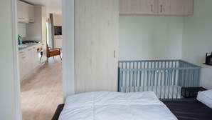 Une chambre moderne avec un berceau, un lit et une vue sur la cuisine et le salon.