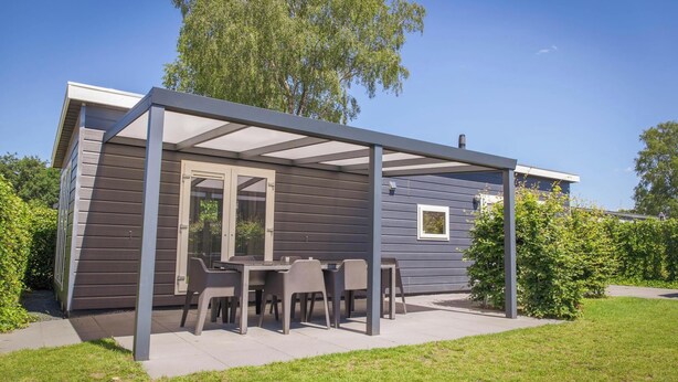 Une maison moderne dotée d’un patio couvert, d’une table à manger et de chaises.