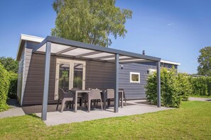 A modern house with a covered patio area, a dining table, and chairs.