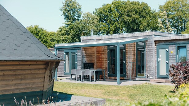 Una casa moderna con un porche cubierto, piscina y terraza de madera.
