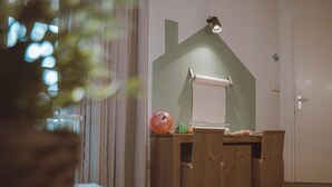 Una habitación con un escritorio de madera, una pizarra, una planta pequeña y una puerta.