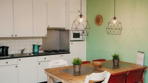 Una cocina moderna con armarios blancos, un microondas y una mesa de comedor de madera con sillas rojas.