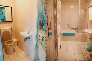 Une salle de bain comprenant des toilettes, un lavabo, une douche et un mur décoratif.