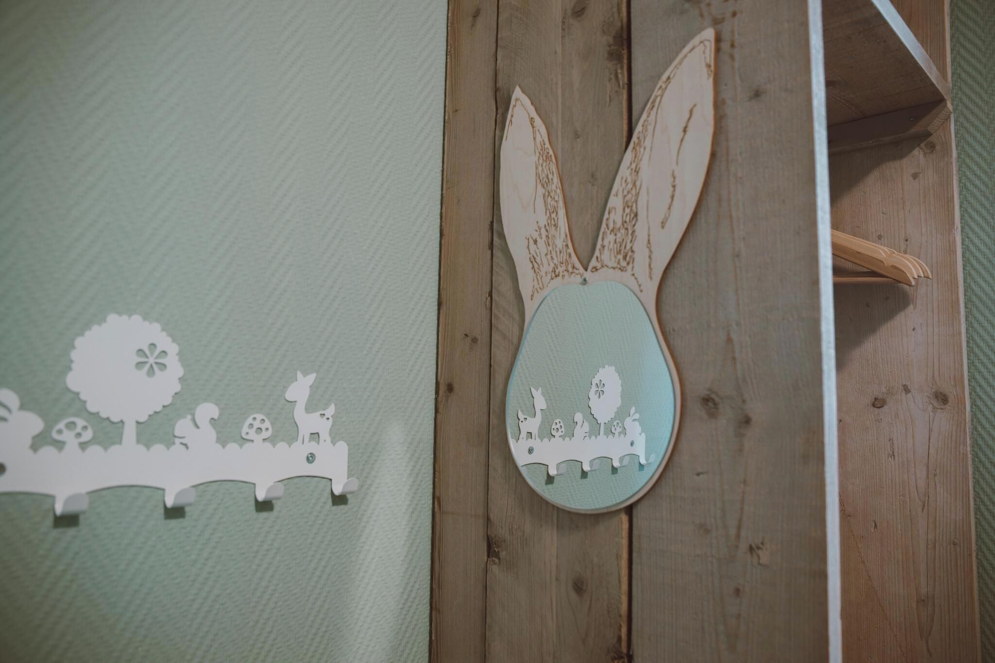 Un mur en bois orné d’une décoration représentant un lapin blanc et d’une scène découpée dans du carton blanc, représentant des animaux et des arbres.