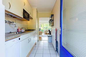 Una cucina piccola con un forno a microonde, fornello e lavello.
