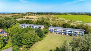 A hotel with two-story buildings, surrounded by greenery and fields, with a view of the landscape.