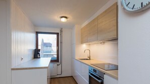 Eine kompakte Küche mit integriertem Backofen, Spüle und Fenster mit Blick auf die Stadt.